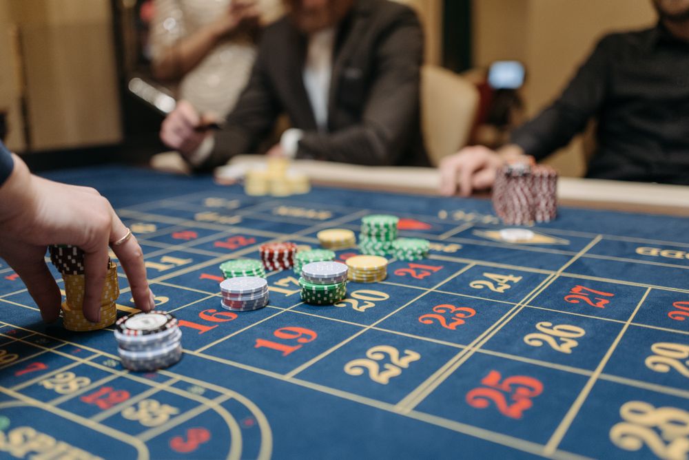 Tangan pemain menempatkan chip di meja roulette sebagai ilustrasi anggaran bermain