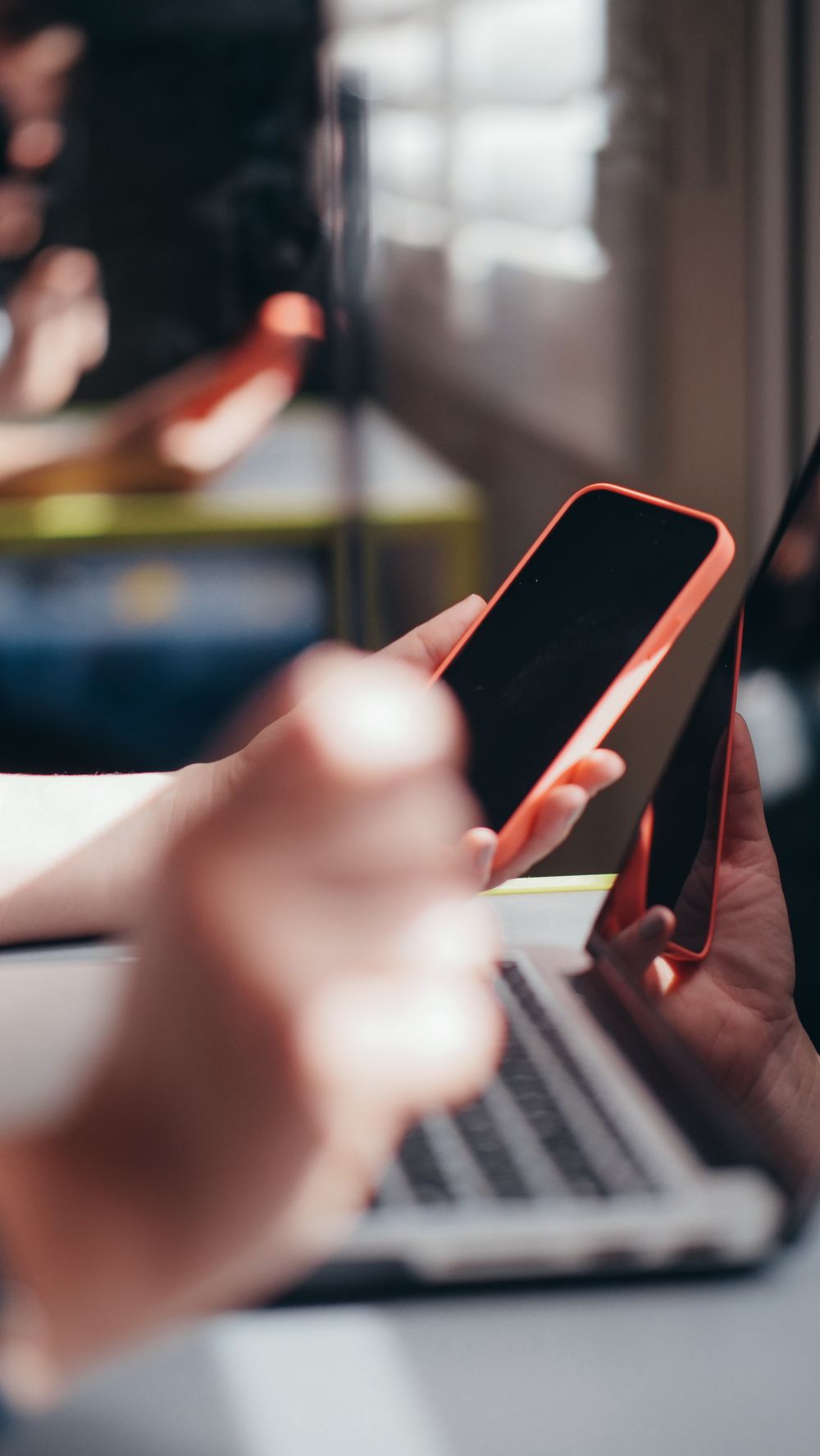 Tangan memegang smartphone di dekat laptop untuk meneliti platform