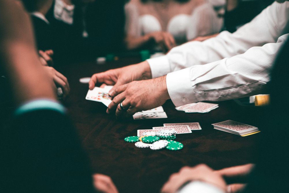 Pemain poker memegang kartu di meja dengan tumpukan chip